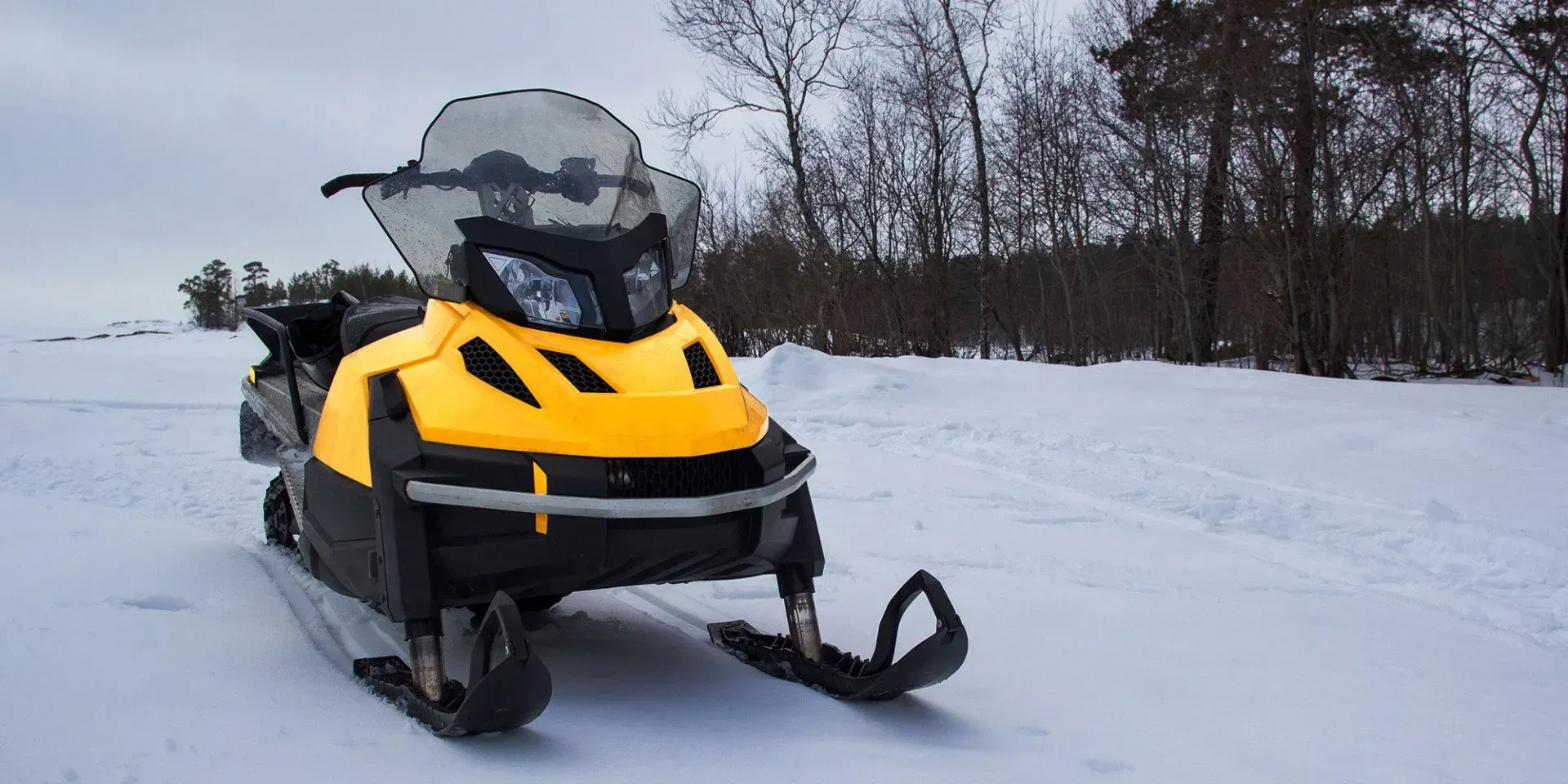 Person on green ATV with snow plow, clearing snow in a winter setting.